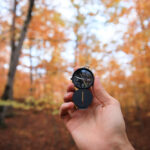 Explorer using a small compass in the woods