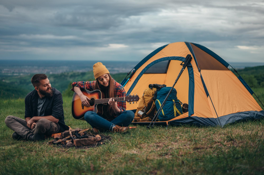 Couple of campers playing guitar while camping in the nature
